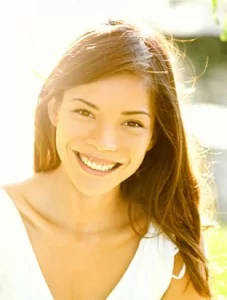 A young woman smiling happy after cosmetic dentistry treatment in Englewood.