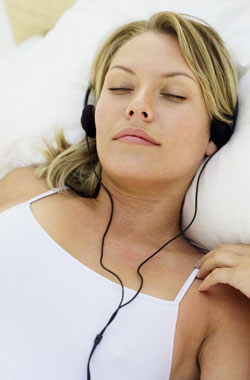 Clayton Dentist Article Woman Laying on Bed with Headphones