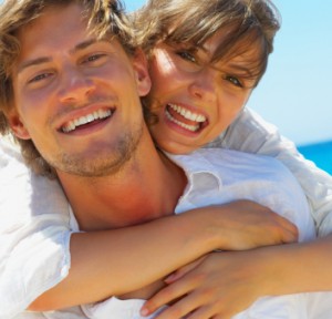 A blonde man and woman smiling outside with porcelain veneers.