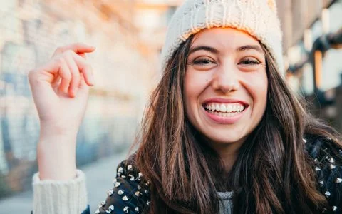 Smiling woman with a hate and long hair received broken tooth treatment at Vitangeli Dental