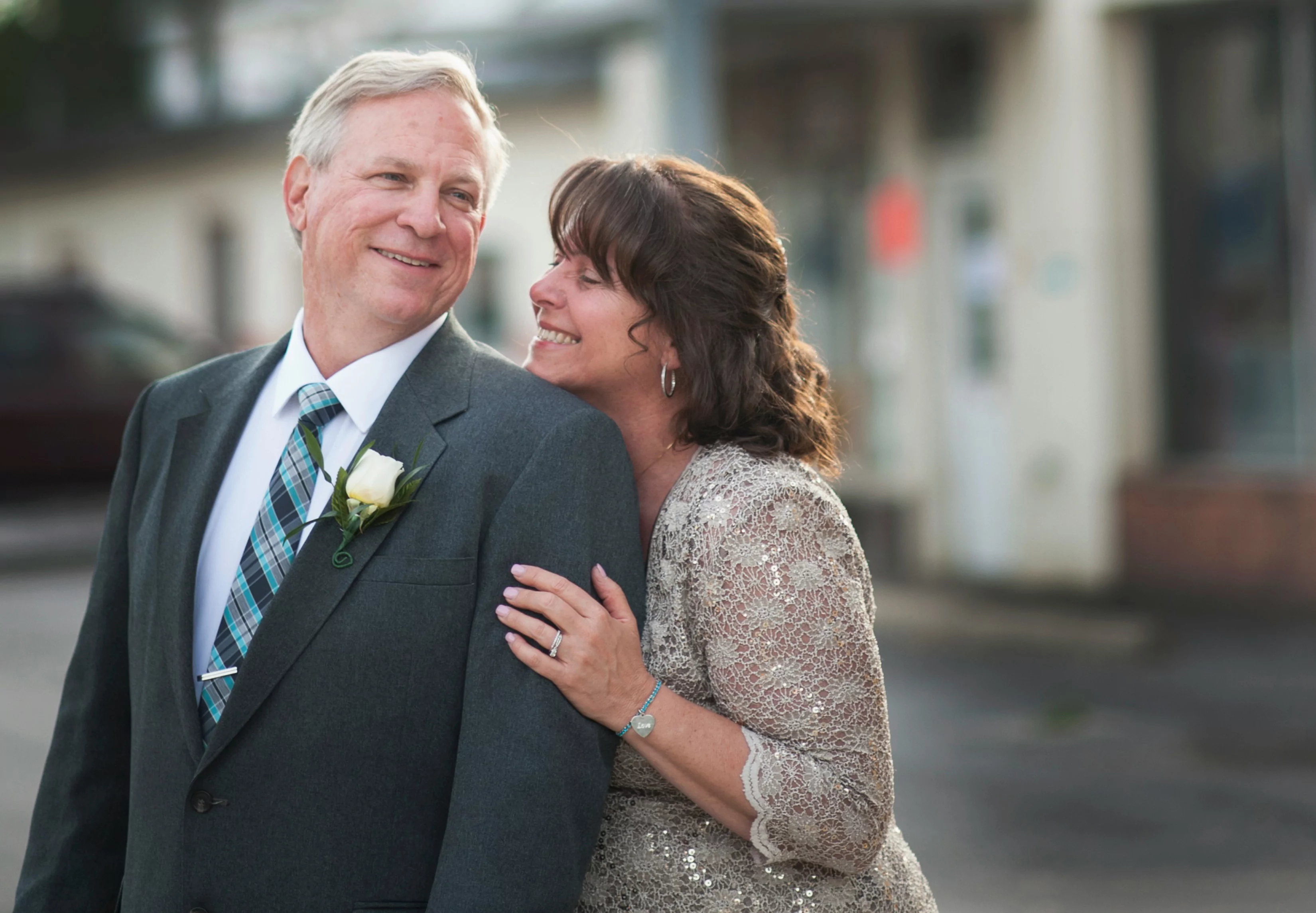 A smiling husband and wife wearing wedding attire