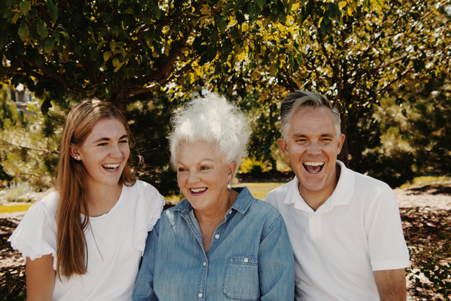 Fixed implant dentures patient poses with her family in a park outside in Englewood, OH