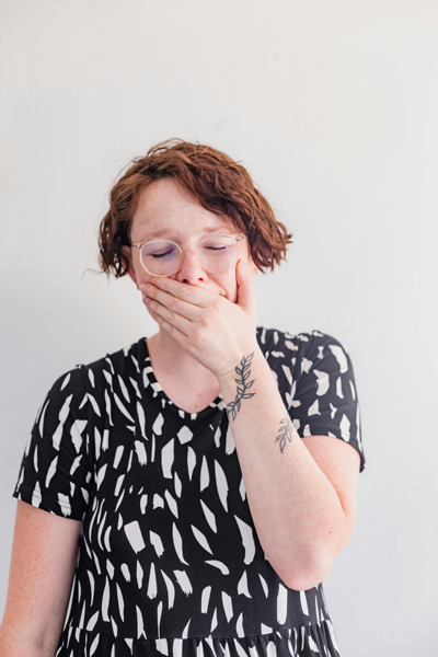 Woman holds mouth with tooth pain due to broken tooth in Brookville, OH